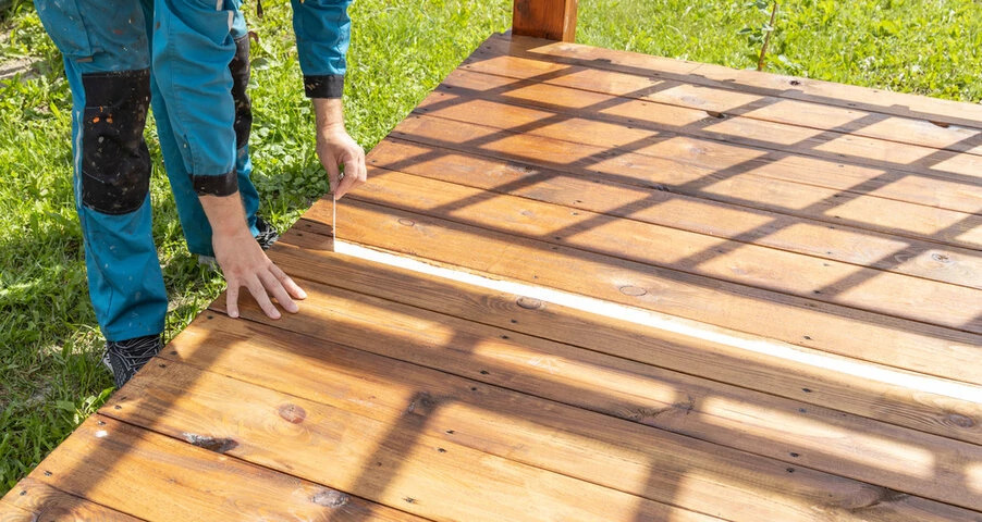 Contractor installing pressure-treated wood decking boards during residential deck construction